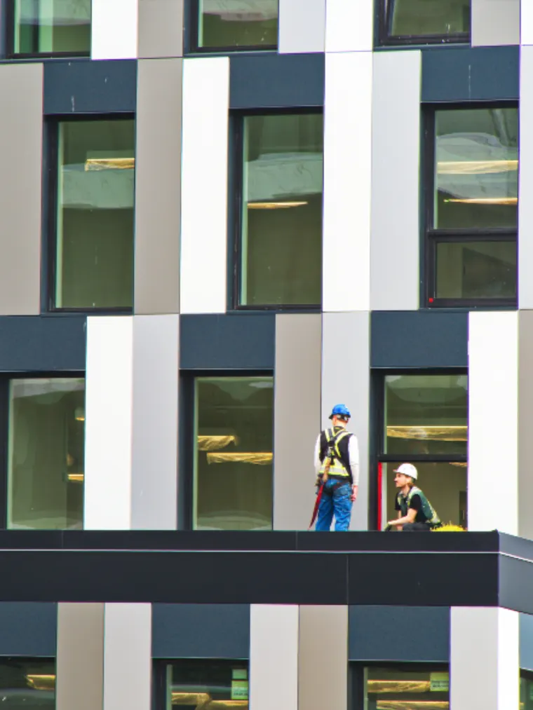 Two workers on a low-slope roof behind a parapet